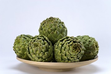 Fototapeta premium Artichokes (Cynara cardunculus) on a wooden bowl