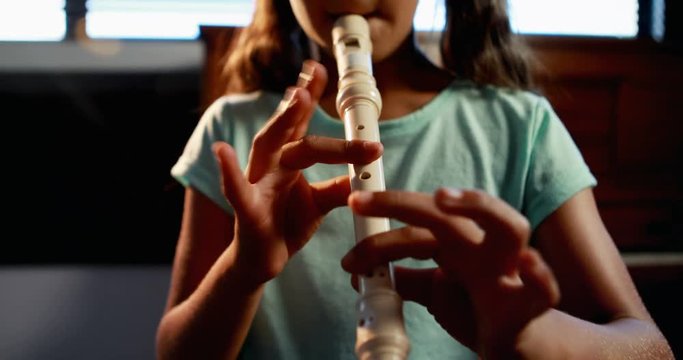Mixed-race schoolgirl playing flute in music class 