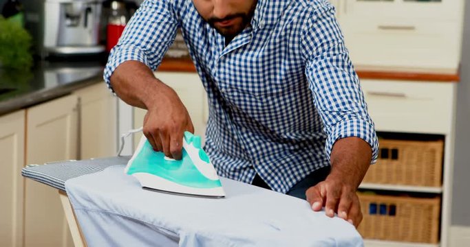 Young man ironing cloth in domestic kitchen from Pikwizard