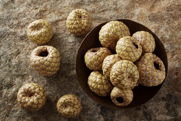 Salak (Salacca zalacca), fruit, in a copper bowl on a stone surface