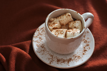 Hot chocolate or cocoa with marshmallows on a background of knit fabrics