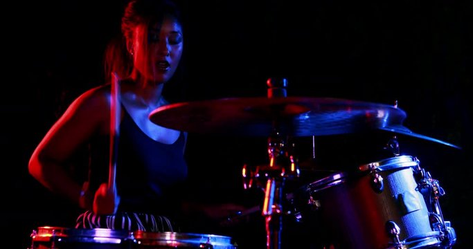 Female drummer playing on drum set 