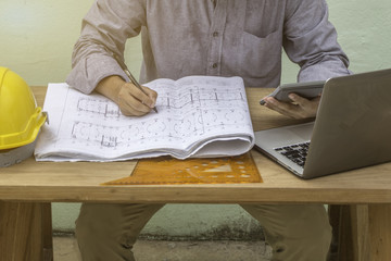 Businessmen or engineers working on accounts using a calculator and writing documents holding a pen...