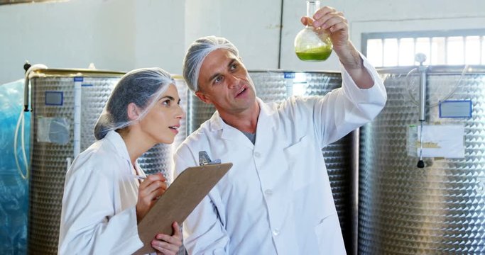 Technicians writing on clipboard while examining olive oil 