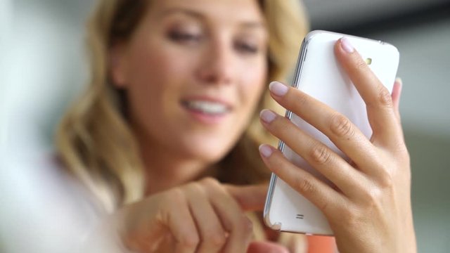Middle-aged blond woman using smartphone