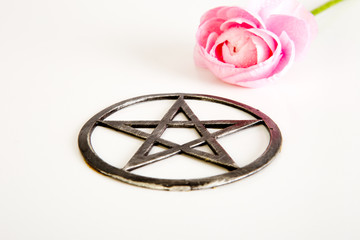 Metal pentagram with pink flower on white background