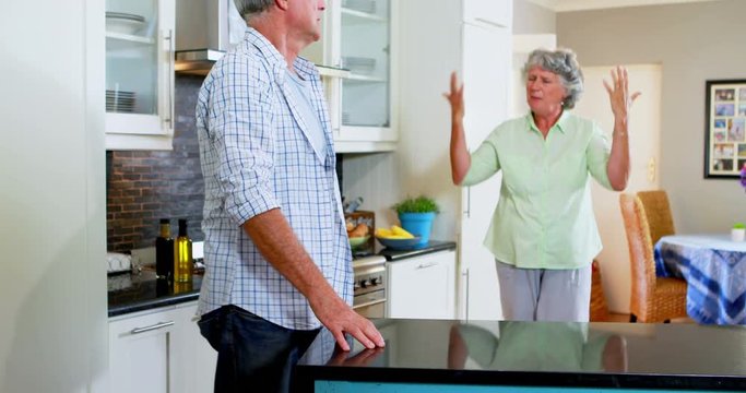 Frustrated senior woman shouting on man in kitchen 