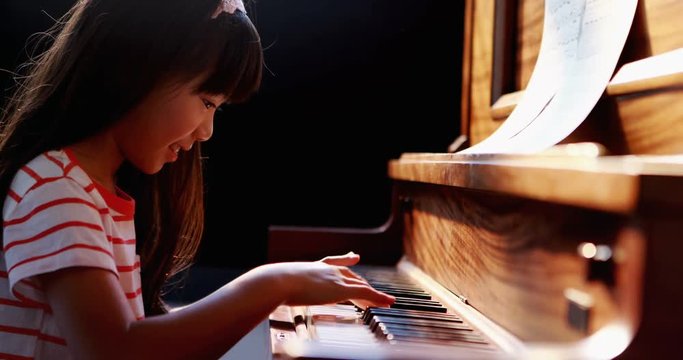Schoolgirl learning piano in music class 