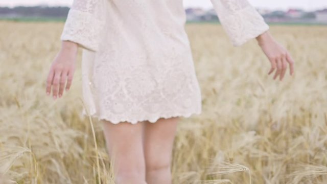 Cropped back view of young woman in dress walking in field