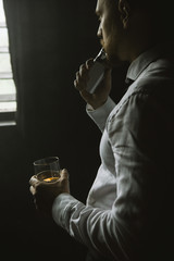 Thoughtful looking male relaxing after work. Man leisure with alcohol and vape in private club, bad habits. Luxury life with whiskey and smoking, dark place background