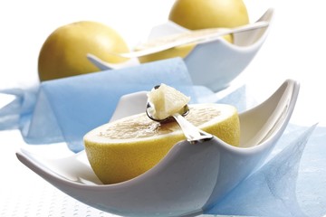 Half of a grapefruit in a porcelain bowl, grapefruit knife, grapefruit spoon