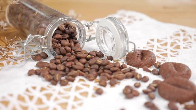 glass jar of coffee bean and coffee cookies set on vintage lace tablecloth background.