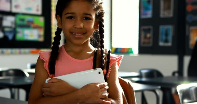 Schoolgirl holding digital tablet in classroom 
