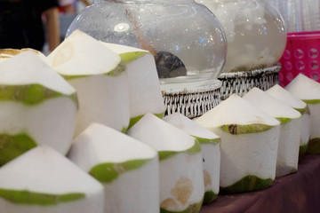 Fresh fragrant coconuts in boat on flea market background, Most pure drink of all the juices