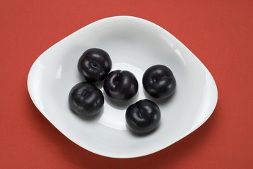 Black Amber Pflaumen (Prunus domestica) in a white bowl