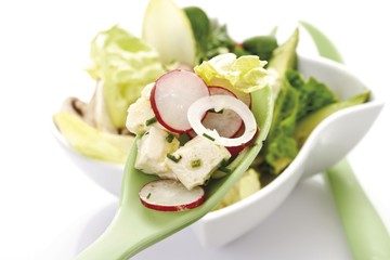 Mixed salad in a small porcelain bowl, feta cheese, feta cheese, avocados, lettuce, corn salad, chicory, onions, radishes, chives, salad servers