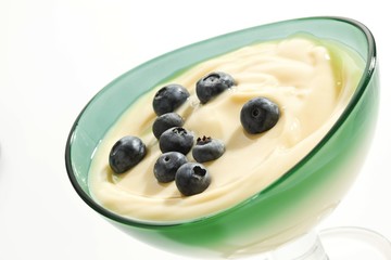 Vanilla pudding with blueberries and raspberries in a glass bowl
