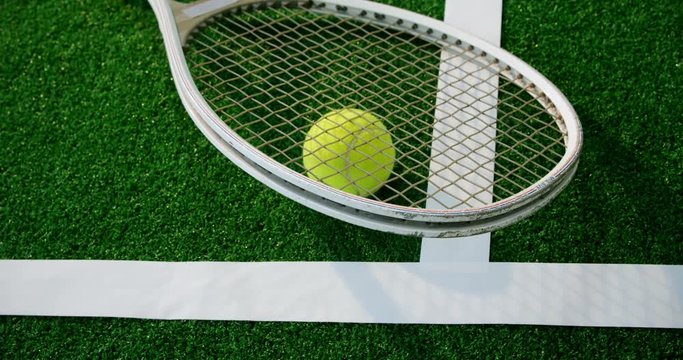 Tennis ball and racket near white line 
