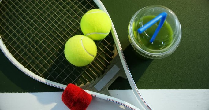 Juice and sports equipment in tennis court 