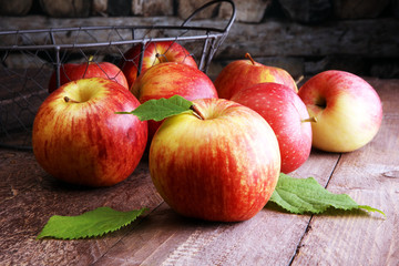 Ripe red apples with leaves on wooden background