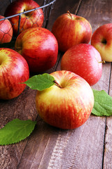 Ripe red apples with leaves on wooden background