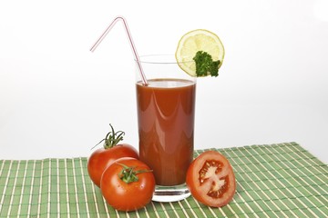 Tomato juice in a glass with tomatoes and lemon