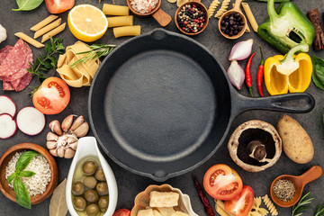 Italian food cooking ingredients on dark stone background with  cast iron pan flat lay and copy...