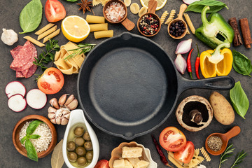 Italian food cooking ingredients on dark stone background with  cast iron pan flat lay and copy space.
