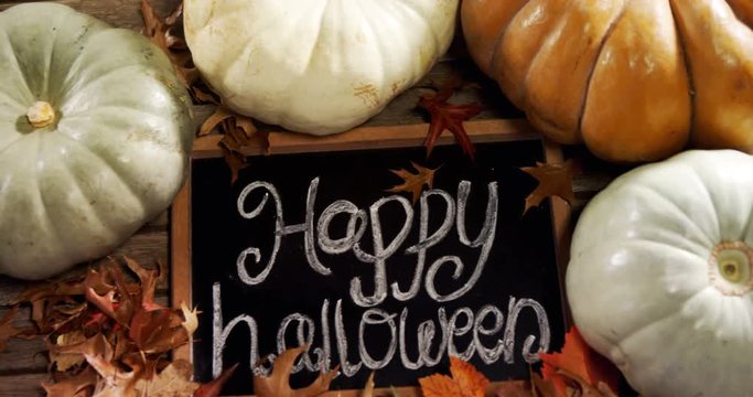 Happy halloween text written on slate with pumpkin 