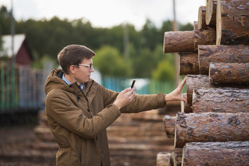 Businessman with phone in a warehouse of lumber