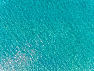 Aerial top view of sea surface. Transparent turquoise ocean water surface from drone.