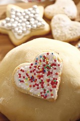 Heart-shaped shortcrust cookie with sugar pearls on a ball of dough