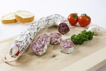 Gourmet salami, premium salami with French bread, garlic tomatoes and parsley on a wooden board