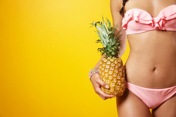 Beautiful young woman in bikini holding pineapple on color background - obrazy, fototapety, plakaty