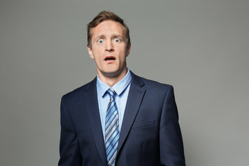 Emotional man in suit on grey background
