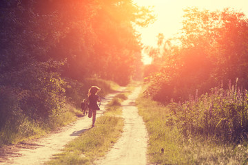 Fototapeta na wymiar A little girl with a dog runs along a country road