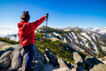 Successful woman at top of Mount Tsubakuro Dake, famous trekking mountain in Azumino, Nagano, Japan. It is situated in Japan's Hida Mountains or Japan Alps.