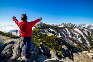 Successful woman at top of Mount Tsubakuro Dake, famous trekking mountain in Azumino, Nagano, Japan. It is situated in Japan's Hida Mountains or Japan Alps.