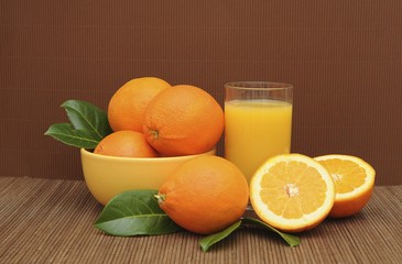 Glass of orange juice beside oranges in a bowl