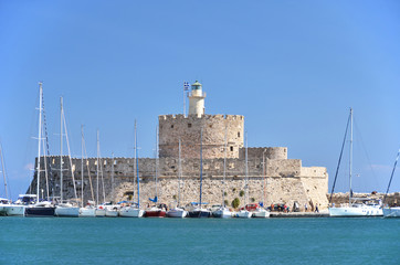 Fototapeta na wymiar Fort of St. Nicholas with the lighthouse in Mandraki harbor, Rho