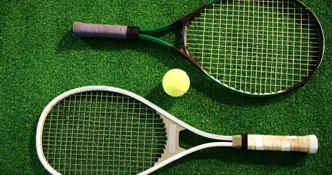 Tennis ball and rackets arranged on grass 