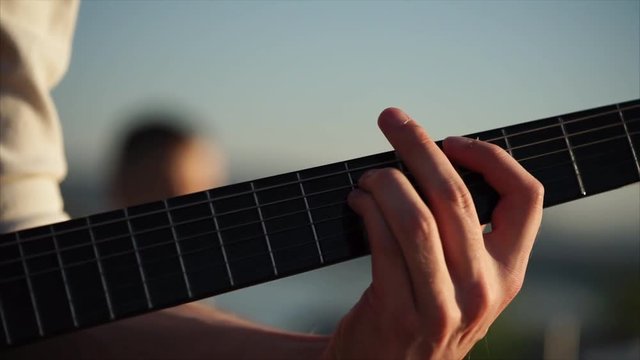 Close-up shot of a man plying solo guitar in music band. View to the hand plucking fingerboard