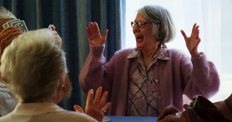 Happy senior friends playing cards - Powered by Adobe