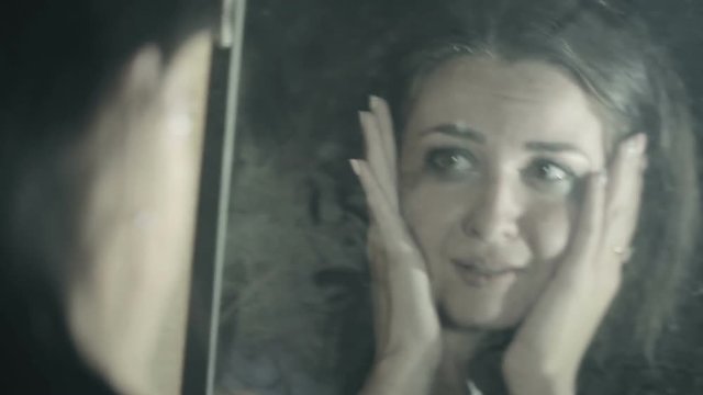sad brunette girl looking at her reflection in the mirror