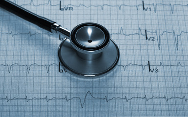 Close up view of stethoscope on electrocardiogram background.