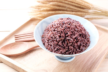 Brown Rice with wooden spoon on wooden background