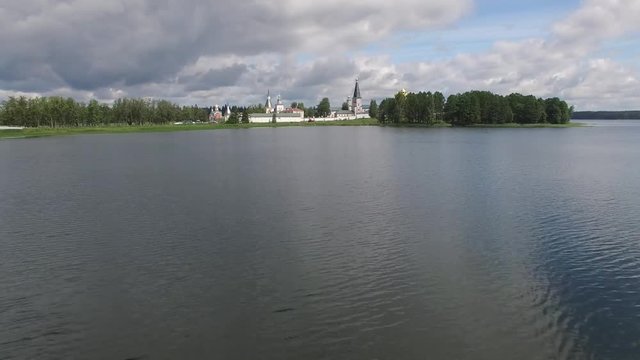 Reflections Valday Iversky Russian Orthodox Monastery. Valdaysky National Park UNESCO Biosphere Reserve Lake Seliger. Flight low to water aerial drone. Beautiful nature summer clouds horizon.