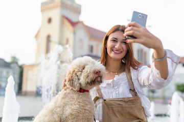 Dogs give us a sense of purpose. Woman taking selfie with her dog outdoor - obrazy, fototapety, plakaty