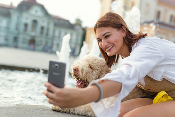 Dogs give us a sense of purpose. Woman taking selfie with her dog outdoor - obrazy, fototapety, plakaty
