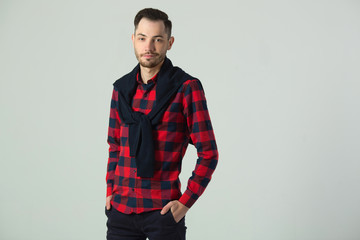 handsome young guy in checkered shirt in studio on wall background